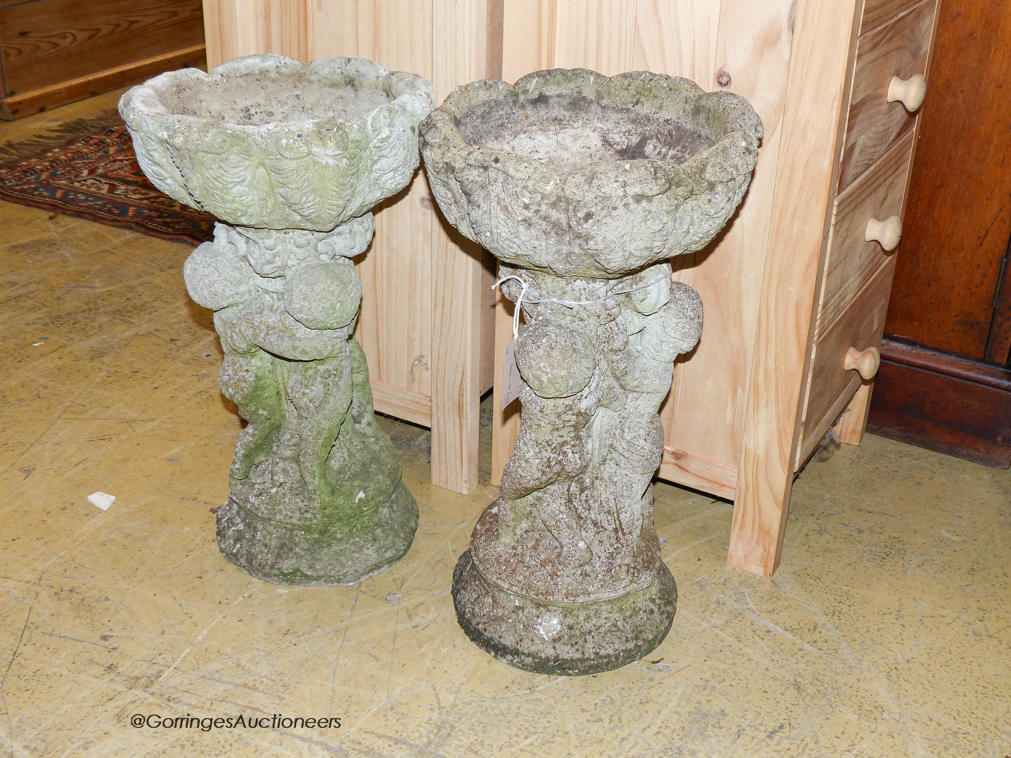 A pair of reconstituted stone circular tulip form planters on figural cherub plinths, diameter 29cm, height 55cm